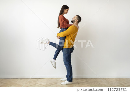 Romantic young man holding and hugging his beloved girlfriend at home 112725781