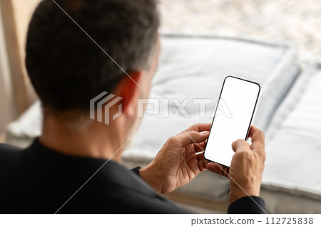 Over-the-shoulder view of a senior businessman in a dark blazer attentively Over-the-shoulder view of a senior businessman in a dark blazer attentively 112725838