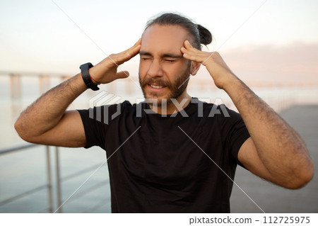 Sporty man touching his temples feeling pounding headache outdoor 112725975