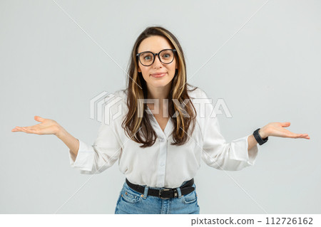 A young woman with glasses and a friendly expression stands with her arms open 112726162