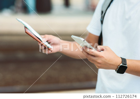 Cropped of man holding ticket and smartphone Cropped of man holding ticket and smartphone 112726174