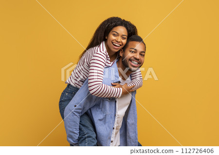 Happy laughing young black couple having fun against yellow studio background 112726406