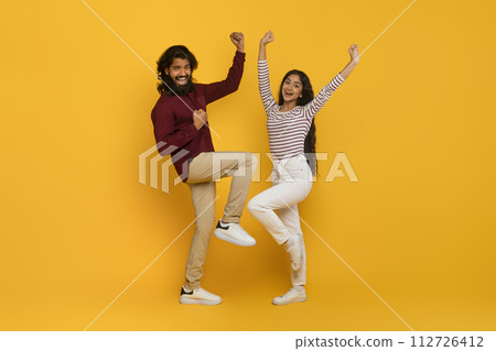 Emotional young indian man and woman gesturing on yellow 112726412