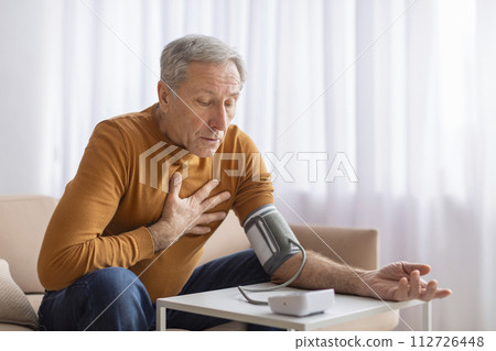 Senior Man Feeling Unwell At Home, Checking Blood Pressure Senior Man Feeling Unwell At Home, Checking Blood Pressure 112726448