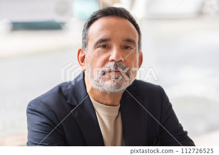 Close-up of a poised mature man with a thoughtful expression Close-up of a poised mature man with a thoughtful expression 112726525