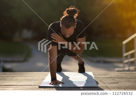 man working out on mat outside doing one hand plank man working out on mat outside doing one hand plank 112726532