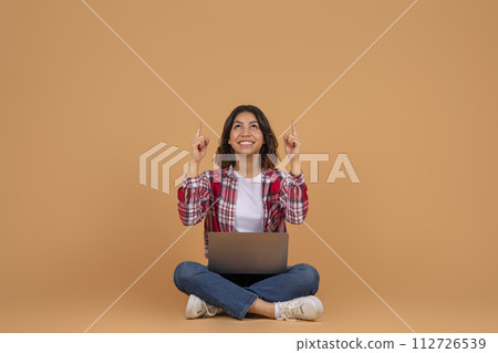 Happy arab woman with laptop pointing up at copy space Happy arab woman with laptop pointing up at copy space 112726539