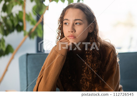 Young teenager girl feeling upset sitting on couch at home 112726545
