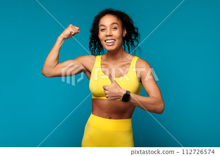 black woman showing her biceps and giving thumbs up, studio 112726574