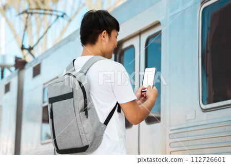 Back view asian guy tourist checking his e-ticket on phone Back view asian guy tourist checking his e-ticket on phone 112726601