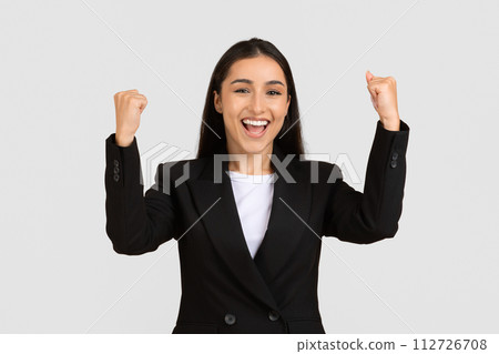 Joyful businesswoman celebrating success with raised fists Joyful businesswoman celebrating success with raised fists 112726708