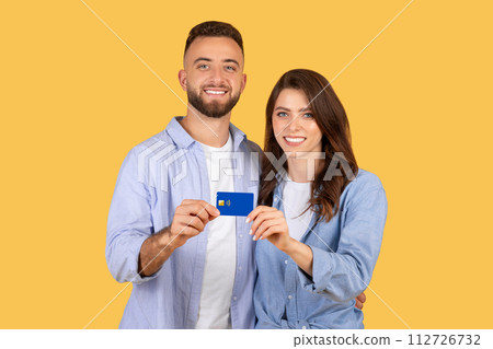 Smiling young couple holding credit card together 112726732