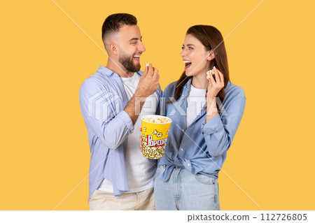 Couple sharing laugh with popcorn bucket Couple sharing laugh with popcorn bucket 112726805