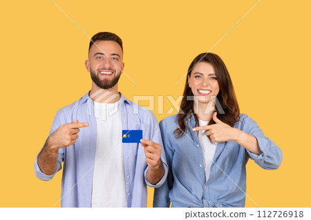 Confident couple pointing at credit card, promoting financial choices Confident couple pointing at credit card, promoting financial choices 112726918
