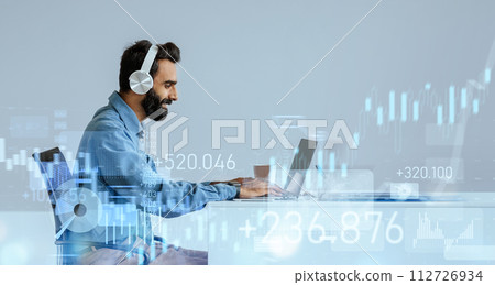 Content bearded man in a blue shirt enjoys music on his headphones 112726934
