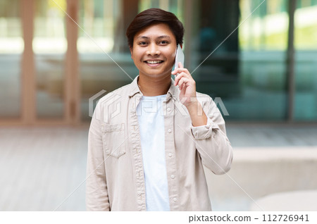 Portrait of cheerful young asian man talking on phone Portrait of cheerful young asian man talking on phone 112726941