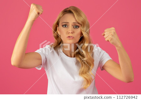 blonde woman posing with arms raised and fists clenched, studio blonde woman posing with arms raised and fists clenched, studio 112726942