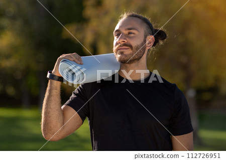 Young athletic man in sportswear carrying fitness mat outdoor 112726951
