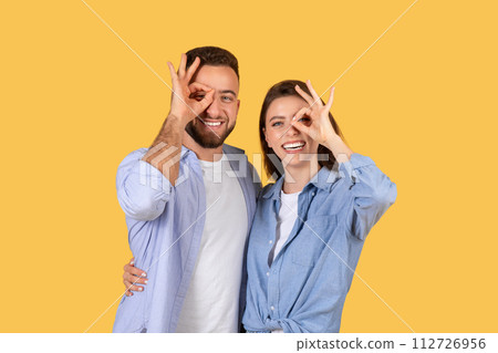 Playful european couple making fun gestures on yellow Playful european couple making fun gestures on yellow 112726956