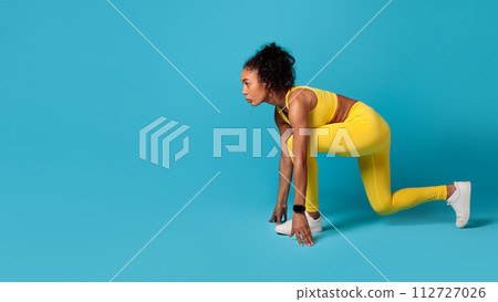 black woman confidently posing in crouch position on blue background 112727026
