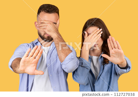 Man and woman covering eyes, showing stop hand gesture 112727038