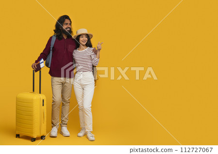 Cool young indian couple tourists pointing at copy space Cool young indian couple tourists pointing at copy space 112727067