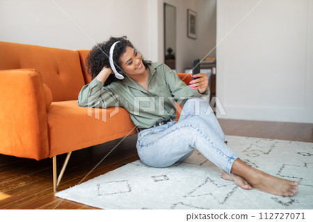 bushy woman at home enjoys her favorite music through headphones 112727071