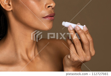 Focused black woman applying lip care product Focused black woman applying lip care product 112727081
