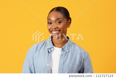 Successful smiling African American woman stands against yellow background 112727124