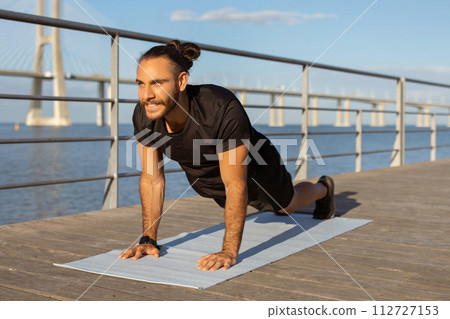 Athletic guy in sportswear making plank exercise during workout outside 112727153