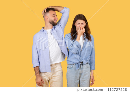 Man sniffs armpit and smiling, woman covers nose 112727228