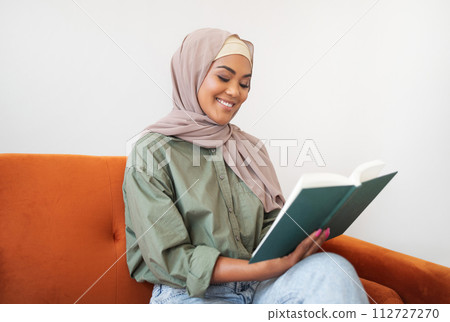 Islamic young woman in headscarf reading book at home 112727270
