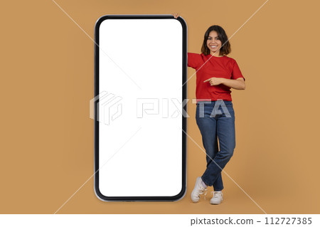 Positive middle eastern lady pointing at huge phone 112727385