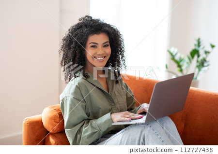 Happy young programmer black woman works on laptop at home Happy young programmer black woman works on laptop at home 112727438