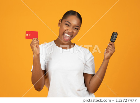 Joyful African woman holding credit card and car key, studio Joyful African woman holding credit card and car key, studio 112727477