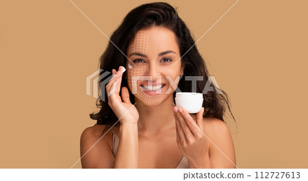 Attractive woman with graphic lines on her face using cream Attractive woman with graphic lines on her face using cream 112727613