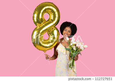 Joyful woman with curly hair celebrating with a golden number 8 balloon Joyful woman with curly hair celebrating with a golden number 8 balloon 112727651