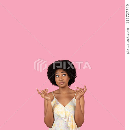 Uncertain African-American woman with fingers crossed, looking upwards and hoping for the best Uncertain African-American woman with fingers crossed, looking upwards and hoping for the best 112727749