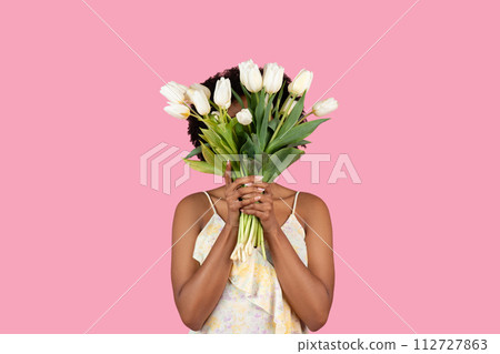 Unseen African American woman standing behind a large bouquet of fresh white tulips Unseen African American woman standing behind a large bouquet of fresh white tulips 112727863