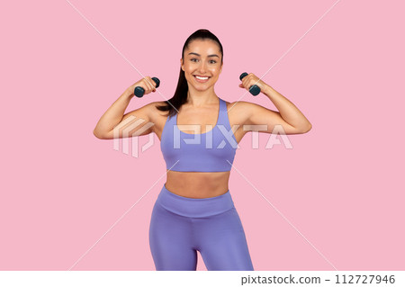 Strong woman flexing muscles with dumbbells 112727946