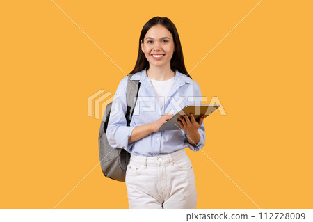 Smiling female student with tablet and backpack on yellow background 112728009