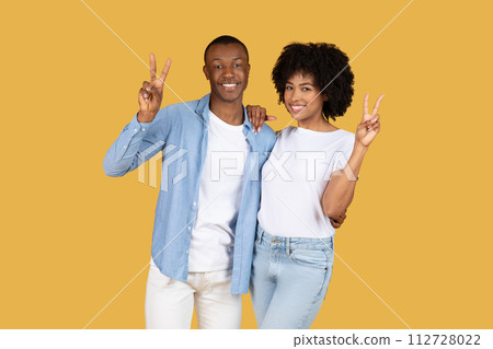 A cheerful young couple wearing casual clothes making peace signs A cheerful young couple wearing casual clothes making peace signs 112728022