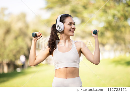 Radiant young woman wearing white workout clothes and headphones Radiant young woman wearing white workout clothes and headphones 112728151