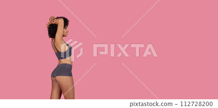 Black fit woman stretching arms in underwear, top and shorts, free space 112728200