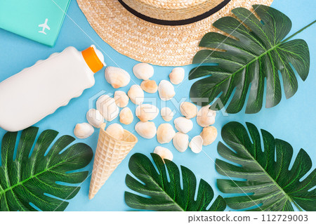 Summer holidays with seashells, palm leaves and straw hat. Blue background. Top view, flat lay. Summer holidays with seashells, palm leaves and straw hat. Blue background. Top view, flat lay. 112729003