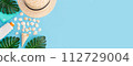 Banner for a summer vacation with shells, palm leaves and a straw hat. Blue background with copy space. Place for text. 112729004