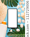 Summer holidays with seashells, palm leaves and straw hat. Phone with white screen. Blue background. Top view. Mockup. 112729006