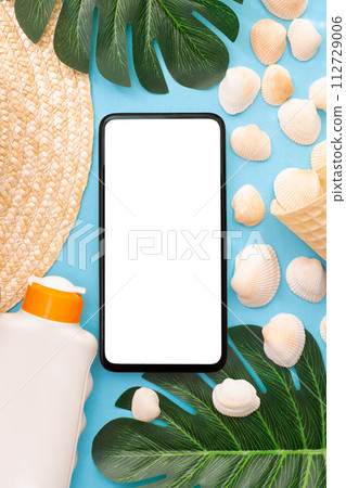 Summer holidays with seashells, palm leaves and straw hat. Phone with white screen. Blue background. Top view. Mockup. Summer holidays with seashells, palm leaves and straw hat. Phone with white screen. Blue background. Top view. Mockup. 112729006