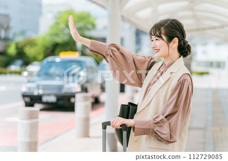一位年輕的亞洲女商人在計程車站舉手叫計程車（出差/轉機） 112729085