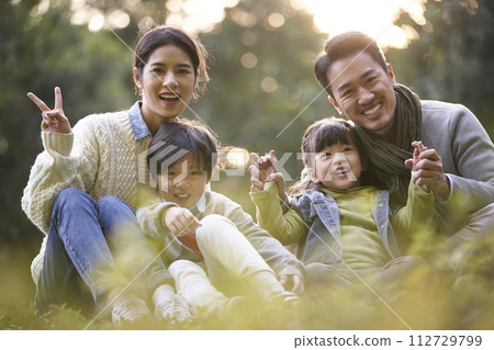 outdoor portrait of a happy young asian family with two children sitting 112729799